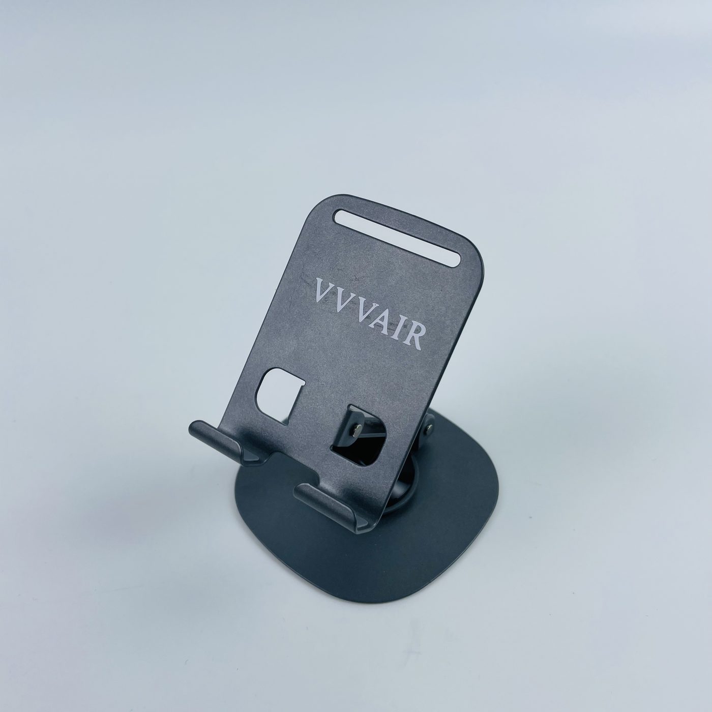 The Space Black mobile phone stand standing upright on a light grey studio background, with the VVVAIR mark printed across the support plate